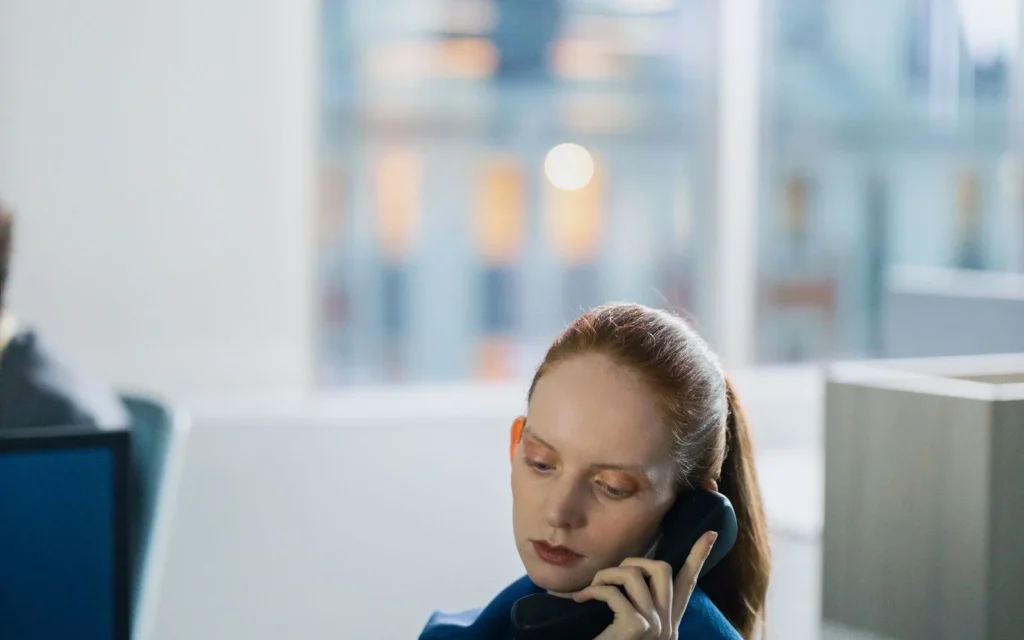 Kvinne på kontor som lytter konsentrert til en telefonsamtale