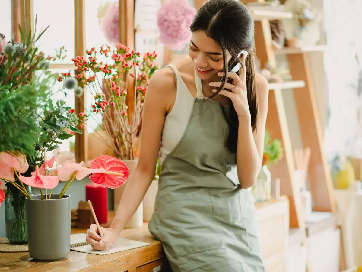 Blomsterhandler i telefonsamtale i butikken sin